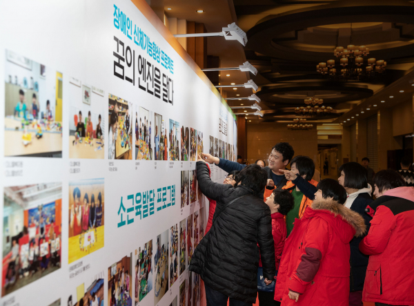 포르쉐 공식 딜러 SSCL '꿈의 엔진을 달다’ 송년 행사에서 참가자들이 소근육 발달 프로그램 참여 사진을 관람하는 모습 (사진=SSCL 제공)