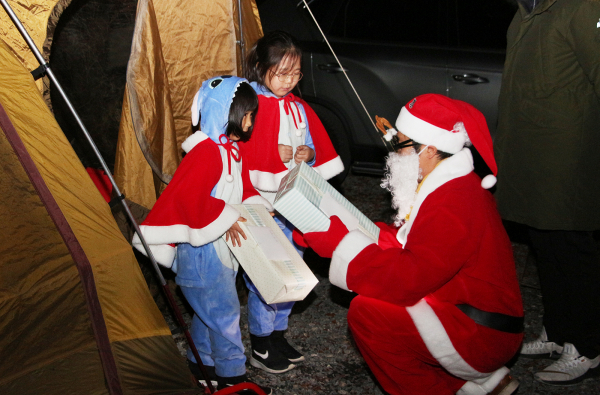 쌍용자동차 미라클 캠프에서 산타클로스 변신한 현장 스태프가 텐트를 깜짝 방문하는 기프트 딜리버리 서비스를 실시했다. 산타의 선물을 받고 기뻐하는 어린이 참가자들의 모습 (사진=쌍용자동차 제공)