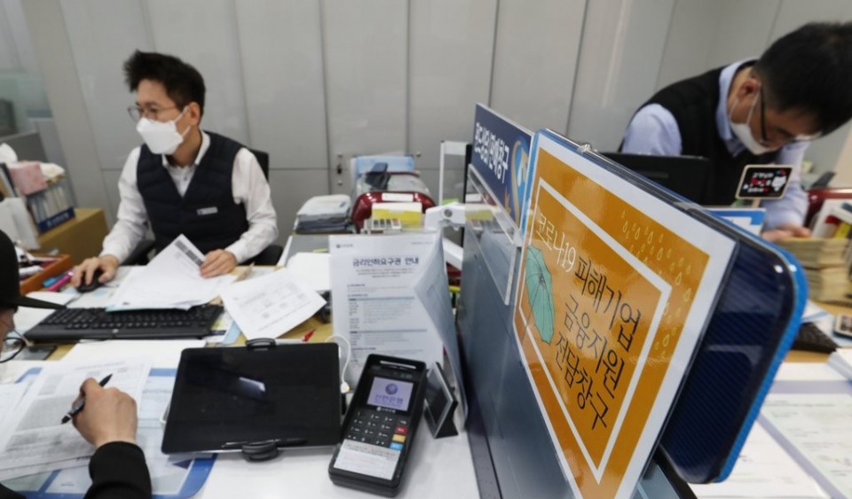 신한은행 직원이 1일 서울시 중구 남대문점에서 코로나19로 피해를 입은 소상공인에게서 대출 신청을 받고 있다. 코로나19로 피해를 본 소상공인과 중소기업은 이날부터 금융기관에 대출 원금 상환 연장과 이자 상환 유예를 신청할 수 있다. 연합뉴스