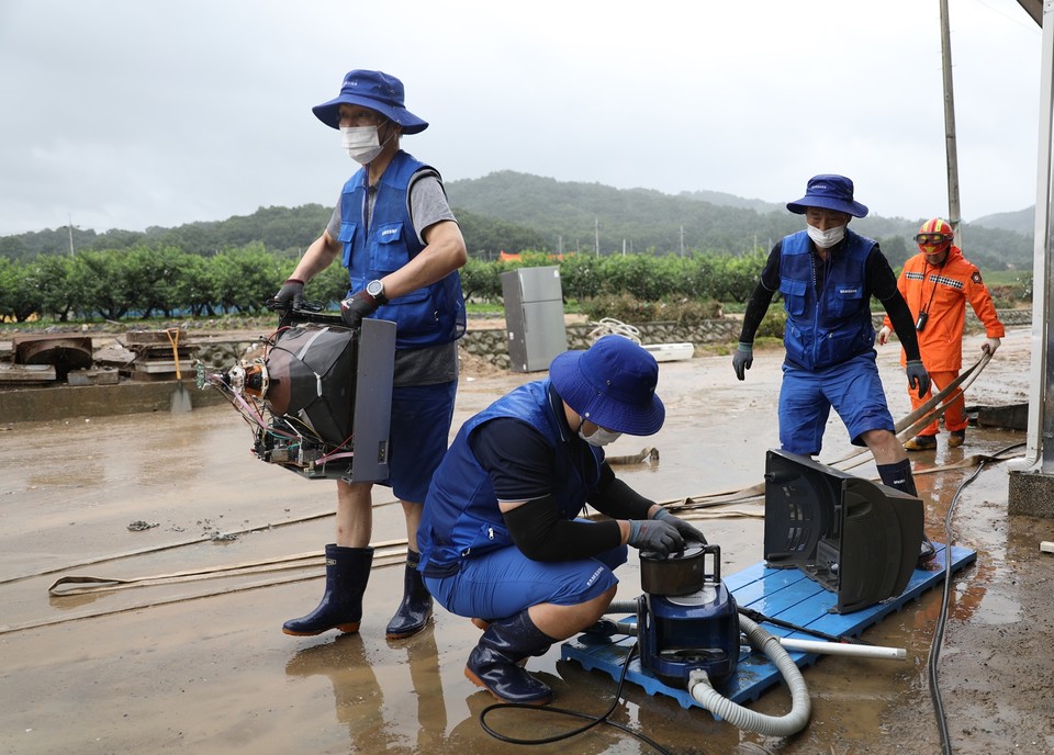 삼성  직원들이 집중호우 피해현장에서 자원봉사를 진행하고 있다. 삼성