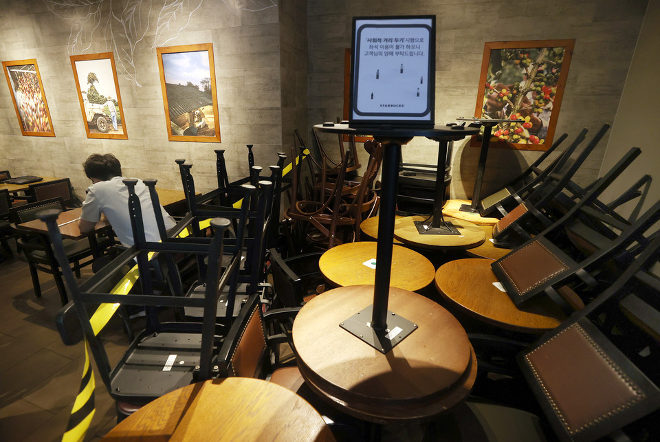 서울 중구 한 스타벅스 매장 한편에 사회적 거리두기를 위해 빼놓은 의자와 테이블이 쌓여있다. 스타벅스코리아는 18일부터 코로나19 확산 방지를 위해 서울과 경기지역 매장의 좌석을 30% 이상 축소해 운영하기로 했다. 사진 연합뉴스