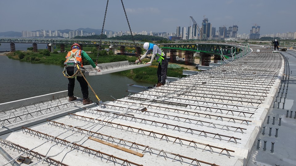 롯데건설이 시공을 맡은 감강보행교 BBCM 공법 시공 전경(탈착식 브라켓 위에 PC 패널을 설치하고 있다. 사진=롯데건설