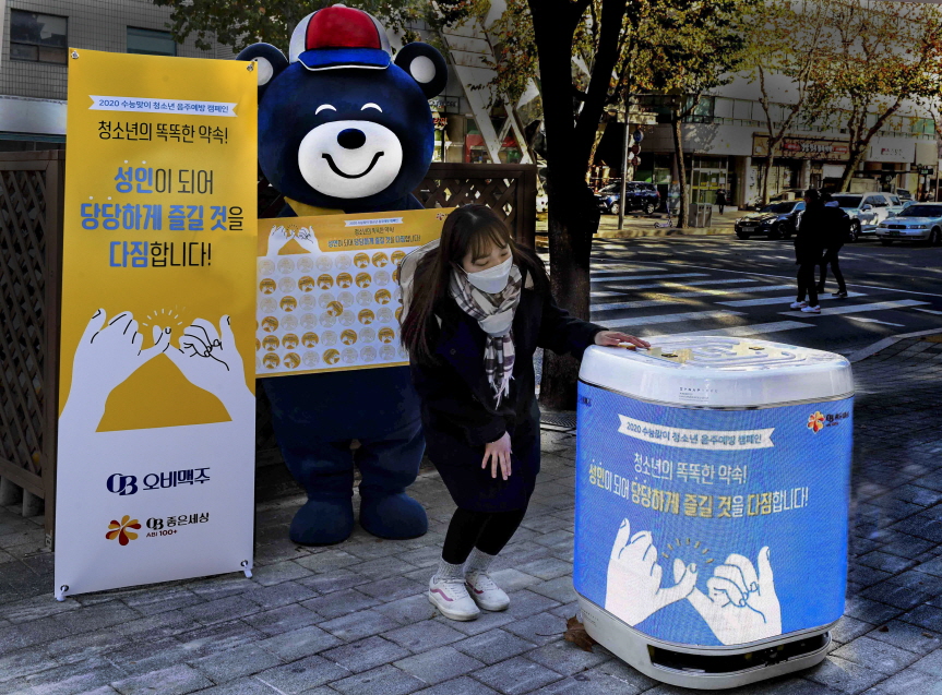 오비맥주는 2021학년도 대학수학능력시험일인 3일 오후 강남구 삼성동 일대에서 비대면 청소년 음주 예방 캠페인을 펼쳤다. 수험생이 자율주행 로봇에게 술은 언제부터 마실 수 있는지 질문하자 “술은 성인이 되어 당당하게 즐기세요”라고 답변하고 있다. 사진=오비맥주
