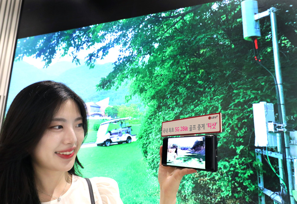 LG유플러스 모델이 레인보우힐스CC에 구축된 5G 28㎓ 기지국 현장 사진을 배경으로 U+골프 서비스를 감상하는 모습 사진=LG유플러스