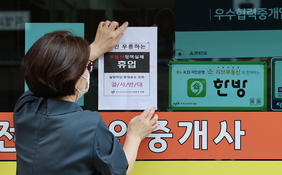 정부가 부동산 중개 수수료 개편을 마련 중인 가운데 19일 오후 서울 시내의 한 부동산중개업소에서 관계자가 중개수수료 인하 정책에 반대하는 휴업 안내문을 붙이고 있다. 연합뉴스