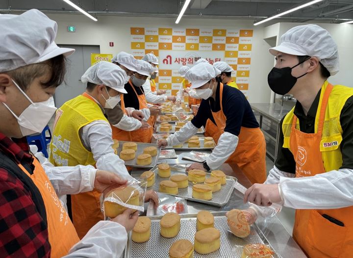SM우방 임직원들이 대구시 서구에 마련된 제빵소에서 제빵봉사를 하면서 행사관계자들과 담소를 나누고 있다. [사진=SM우방]