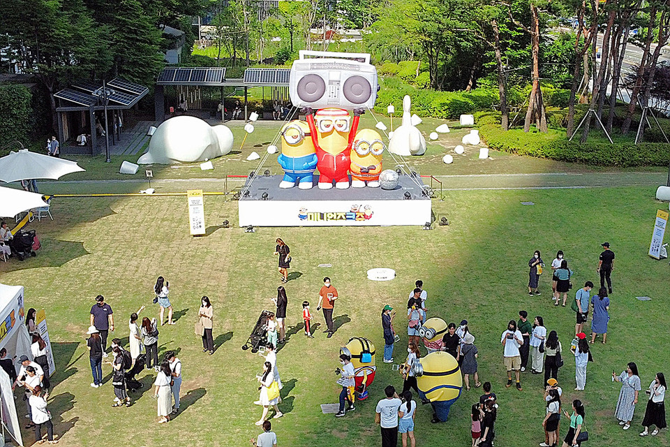 사람들이 미니언즈크쥬와 미니언즈 코스튬과 함께 사진을 촬영하고 있다. [사진=롯데물산]