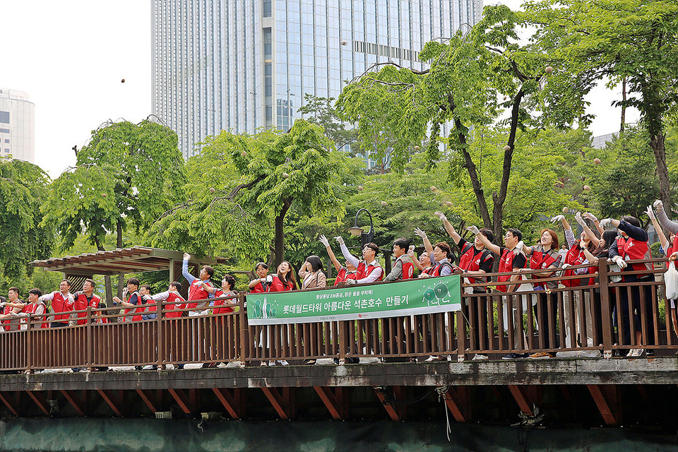  지난 14일 롯데물산 임직원들이 아름다운 석촌호수를 만들기 위한 'EM흙공 던지기' 활동에 동참하고 있다. [사진=못데물산]