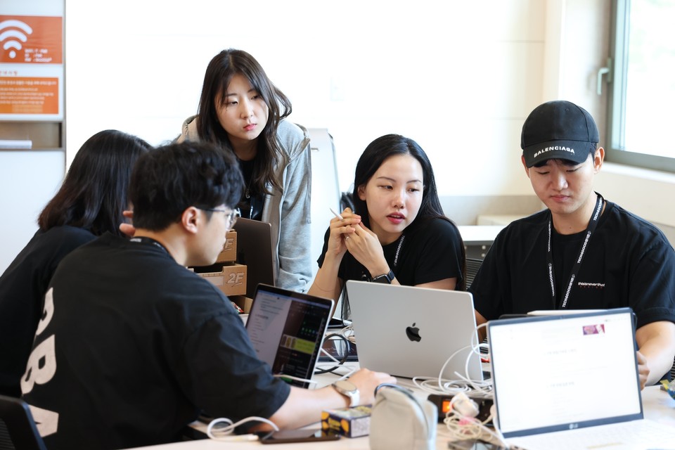 해커톤 현장에서 대학생들이 멘토와 함께 아이디어 회의를 하고 있다. [사진=SKT]